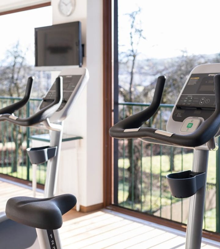 Two exercise bikes facing a large window with outdoor views.