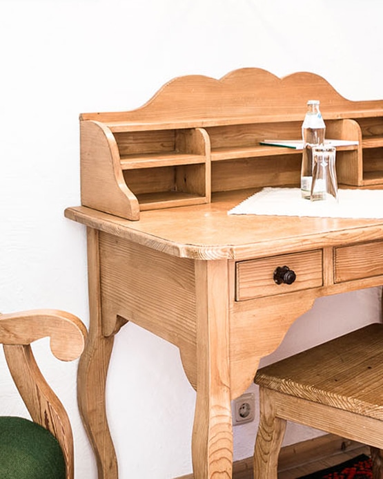 Vintage wooden writing desk with shelves, a drawer, and a bottle of water on top.