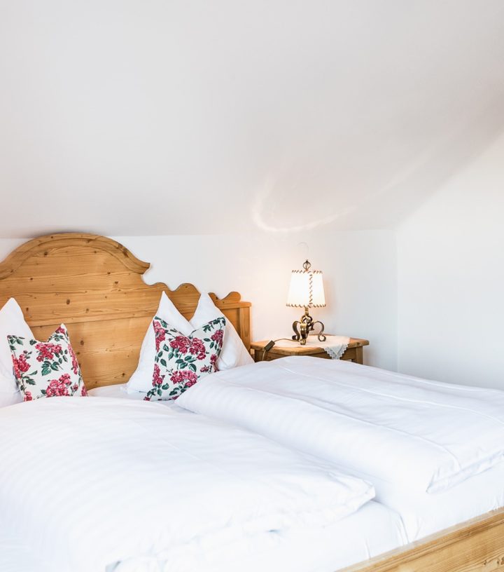 Cozy bedroom with wooden furniture, including a double bed with floral pillows and a matching rustic wardrobe.