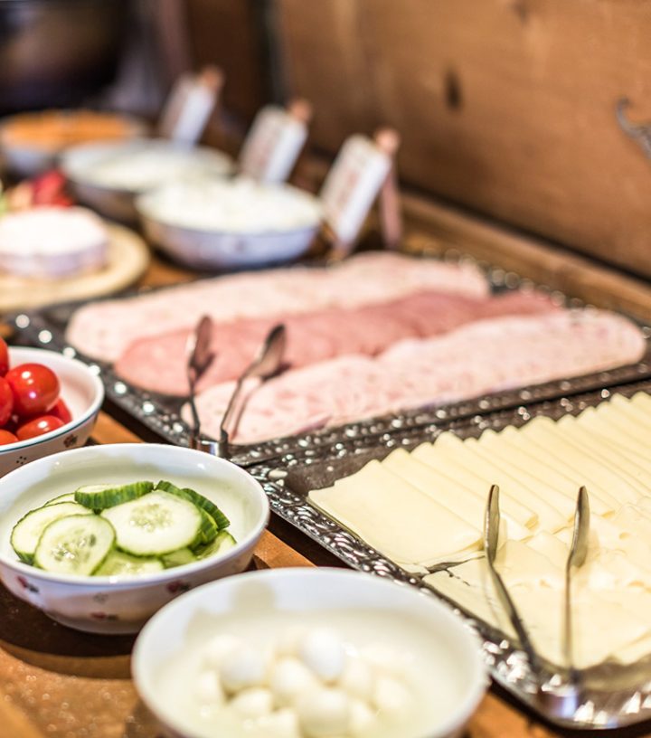 Breakfast buffet selection with sliced meats, cheese, cucumbers, tomatoes, and mozzarella balls.
