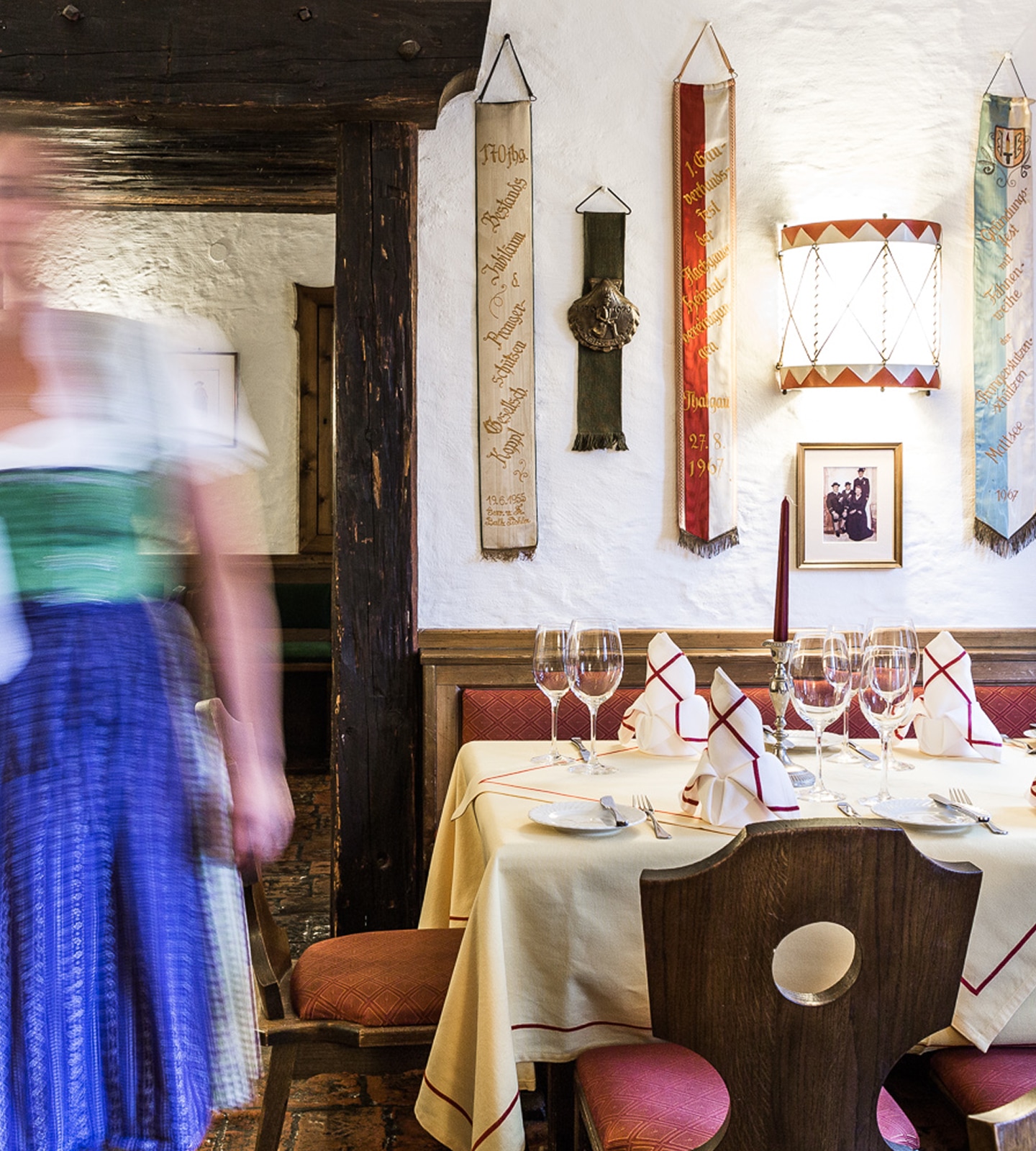 Set dining table in a traditional German restaurant with a blurred waitress in a dirndl walking past.