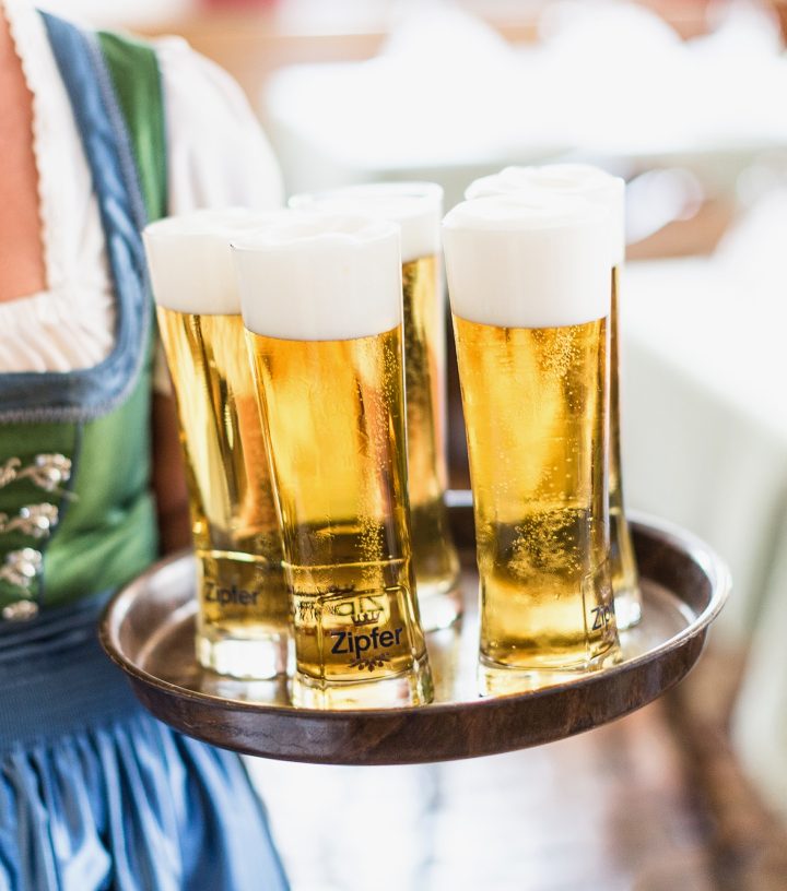A server holding a tray with glasses of Zipfer beer.