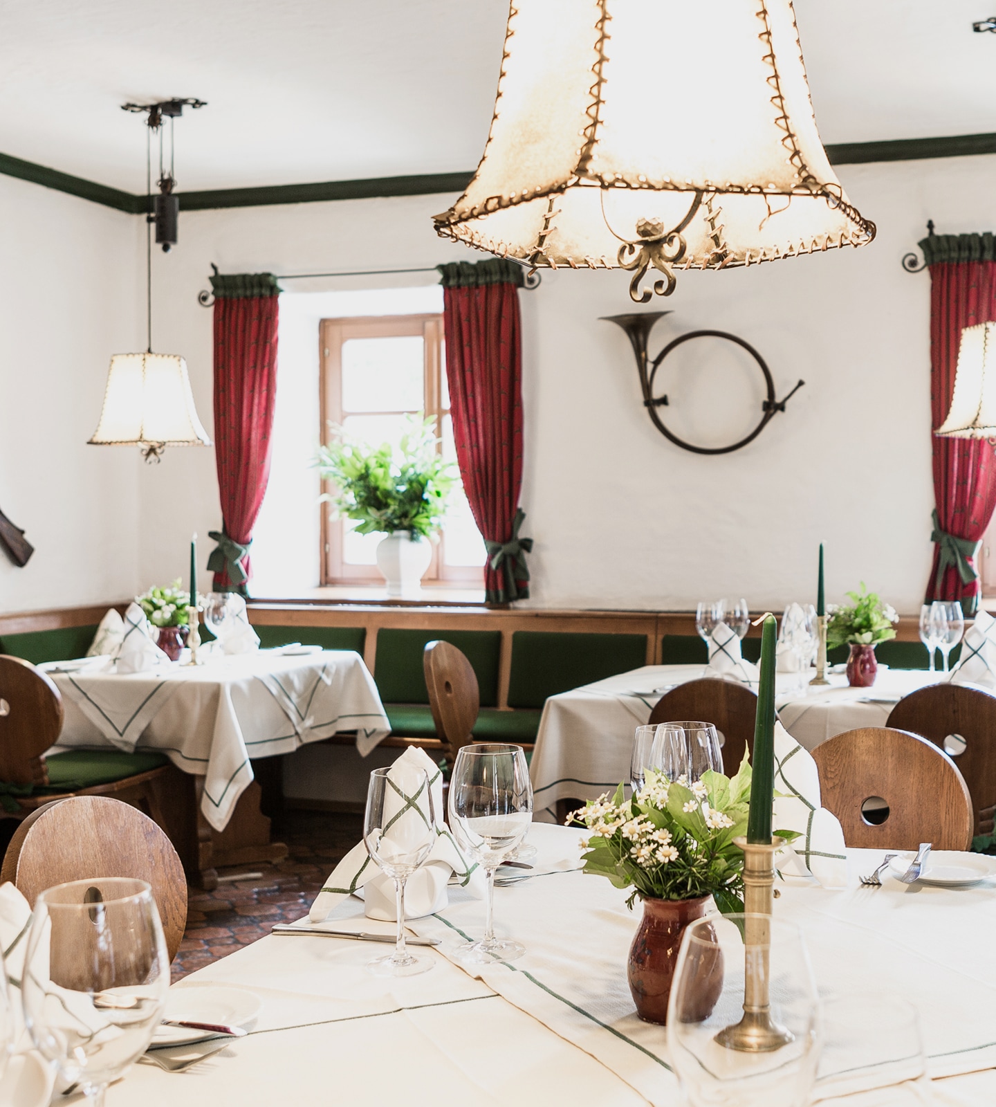 An elegant dining room in a rustic restaurant with set tables, wooden chairs, and traditional decor details.