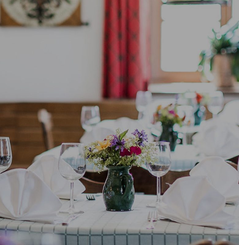 An elegantly set restaurant table with white napkins, wine glasses, and a small floral centerpiece.