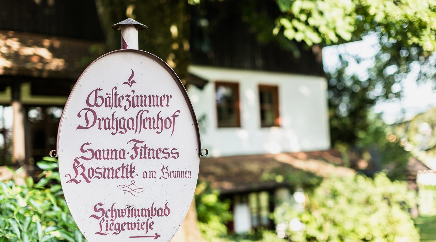 Schild „Gästezimmer Drahgassenhof“ mit Hinweisen auf Sauna, Fitness, Kosmetik und Schwimmbad Liegewiese.