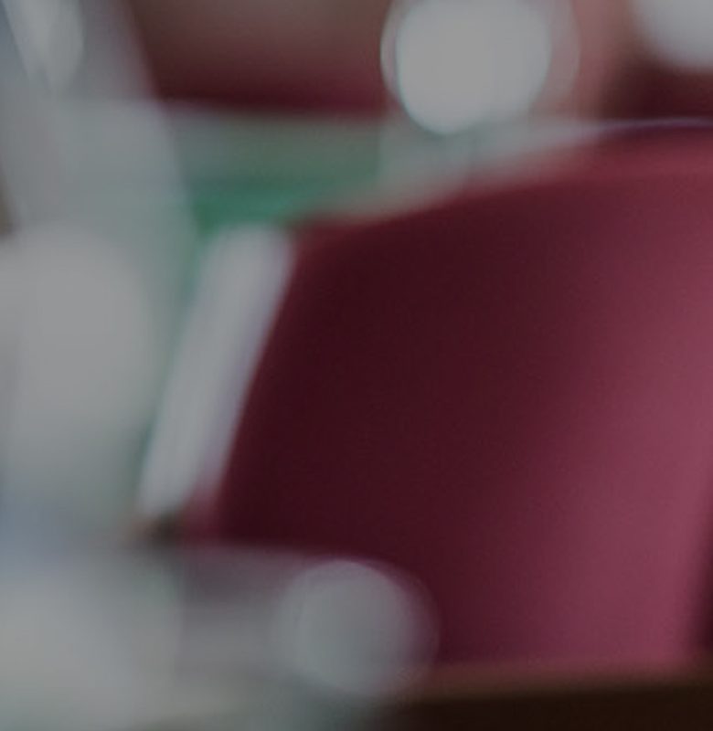Highly blurred abstract view of indoor seating with red chairs, green surfaces, and soft bokeh light.